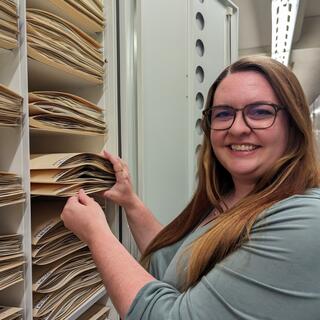 Poindexter works at the National Herbarium at the Smithsonian Natural History Museum, where she helps maintain the preservation quality of the flowering plants collection. Here she is seen handling folders of Astragalus specimens. Photo provided. 