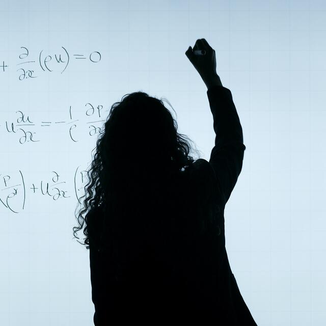 Girl writing a math equation on a white board. Photo by ThisisEngineering RAEng on Unsplash.