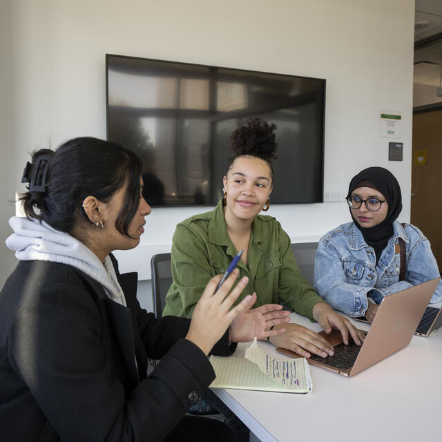 three students in classroom on laptop