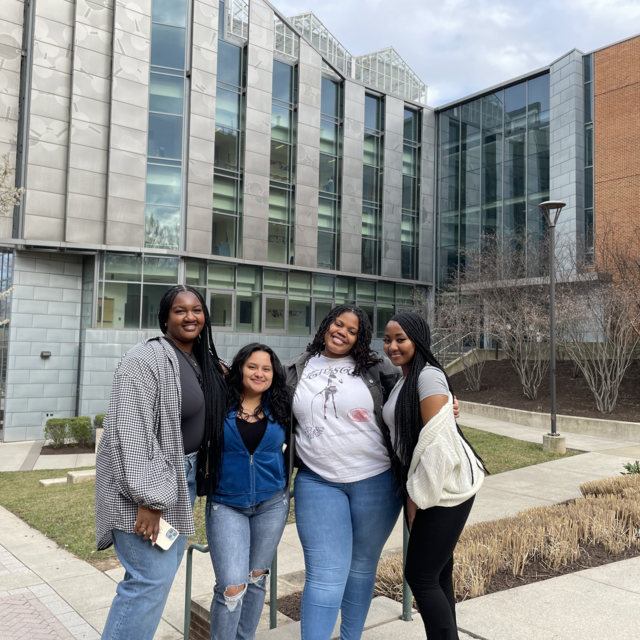 group of 4 students, part of WOCSTEM in front of Exploratory Hall