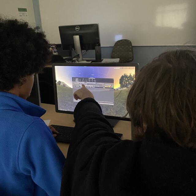 A Counselor and Camper view upcoming celestial events in the Stellarium Planetarium.