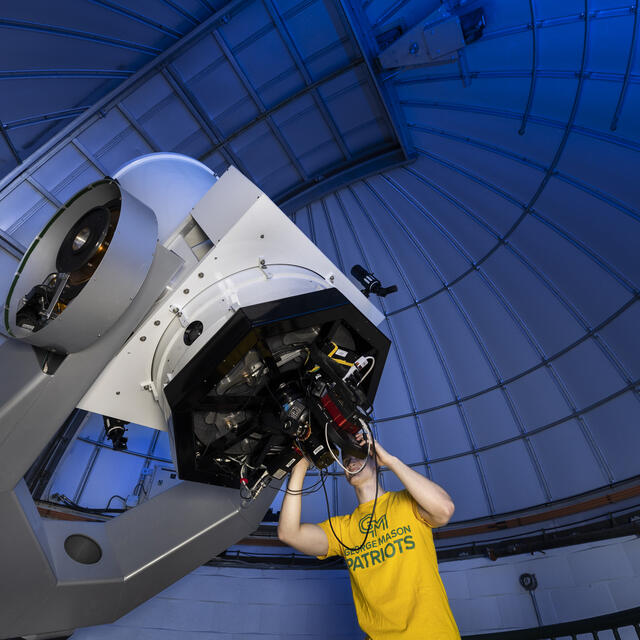 Student looking through telescope in observatory