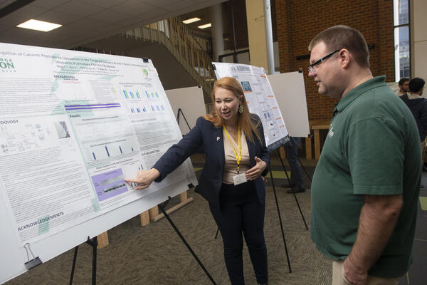 Biology Student presenting poster data to an event attendee