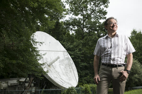 Peter Pachowicz smiles in front of a satellite dish
