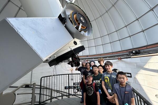 Many students are gathered the Geller Telscope. Here they are below the eyepiece, but as it is daytime, not looking through it.