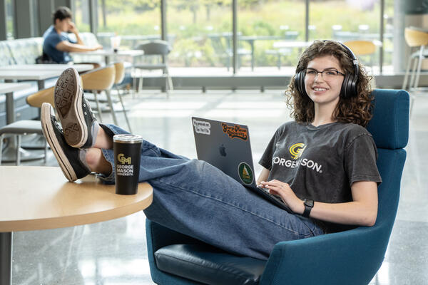 Student sitting at desk with feet up on laptop