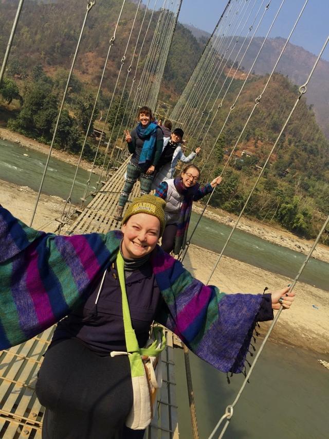 Students give each other courage to walk on the foot bridge swinging in the wind