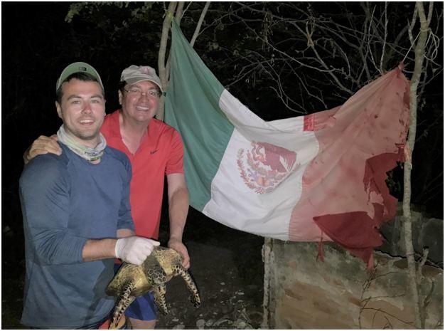 In front of a flag abandoned by fishermen, ESP Chair Dr. A. Alonso Aguirre and his doctoral student Alexander Robillard get ready to release the first hawksbill turtle captured along the Marias Archipelago. Photo Credit: Dr. Cesar Ley-Quiñónez.