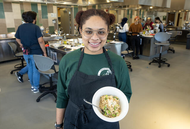 Student showing off her risotto in the Chemistry in the Kitchen class.