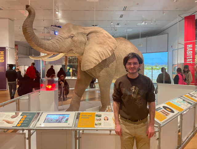 Trent Grasso stands in front of a figure of an elephant.