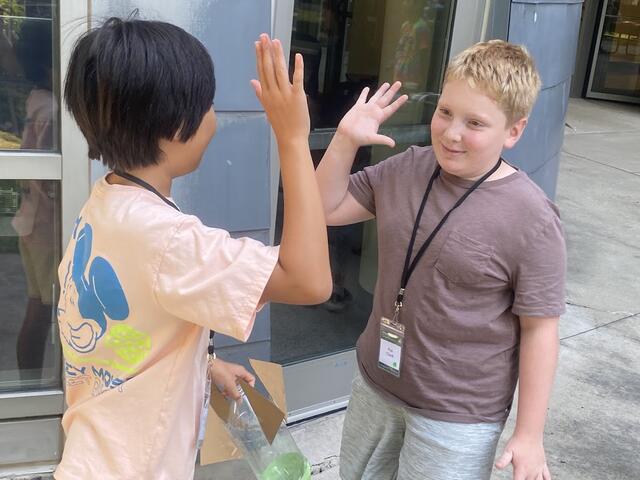 Two campers high five after a successful mission for the day.