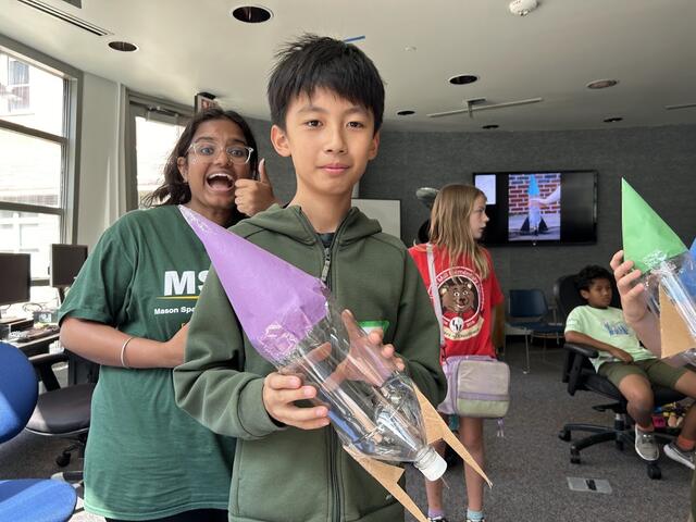 A camper shows of their water rocket. Flight Director Apoorva is seen in the background happily aproving. 