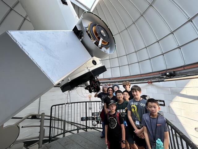 Many students are gathered the Geller Telscope. Here they are below the eyepiece, but as it is daytime, not looking through it.