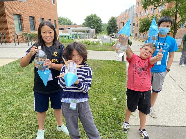 A few campers proudly display their water rockets. One gives a thumbs up.