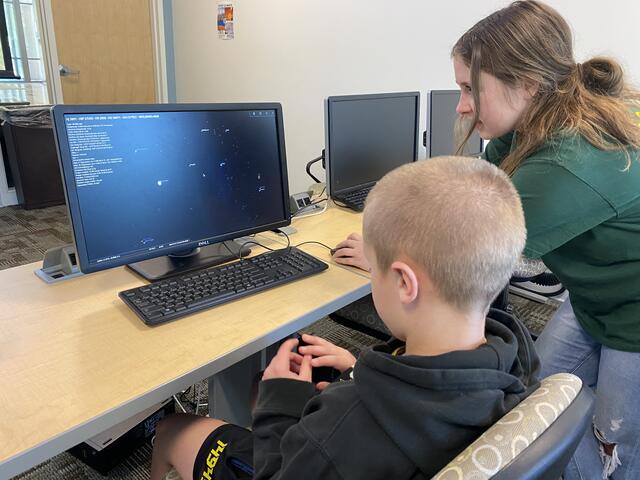 A camper and counselor use the virtual planetarium software together. 