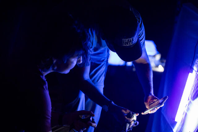 Two participants take photos of insects with the black light