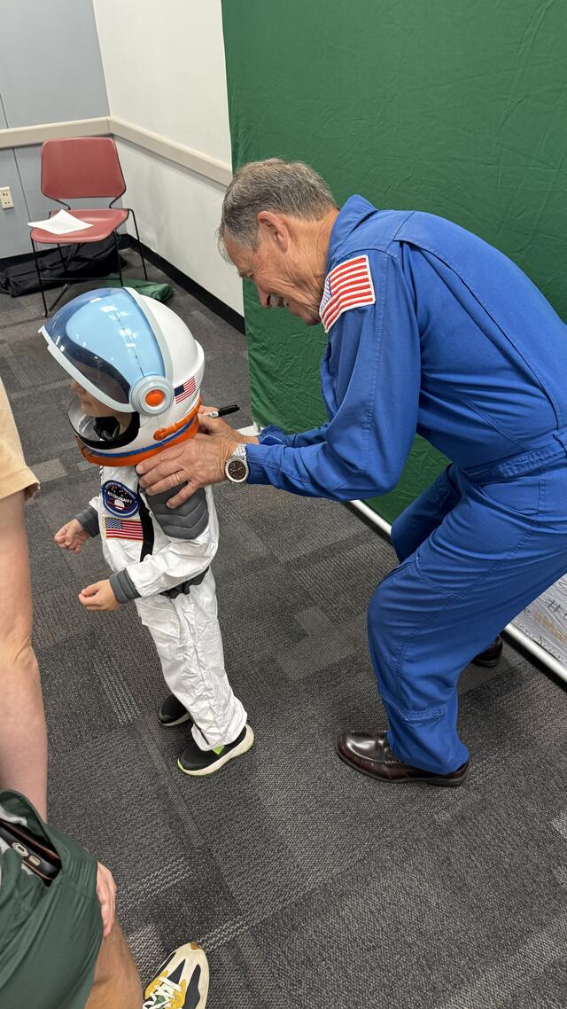 Captain Hoot Gibson signing child's space suit. 