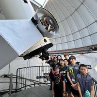 Many students are gathered the Geller Telscope. Here they are below the eyepiece, but as it is daytime, not looking through it.