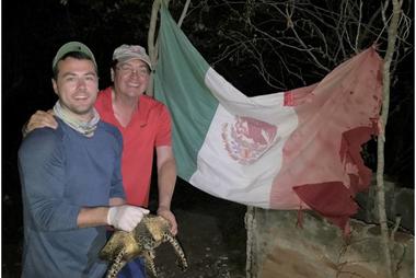 In front of a flag abandoned by fishermen, ESP Chair Dr. A. Alonso Aguirre and his doctoral student Alexander Robillard get ready to release the first hawksbill turtle captured along the Marias Archipelago. Photo Credit: Dr. Cesar Ley-Quiñónez.