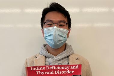 Mason chemistry student Huy Minh Tran holding his infographic