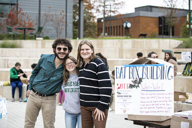Mason students pose next to a Bat Box Building sign
