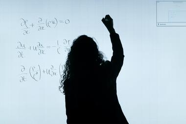 Girl writing a math equation on a white board. Photo by ThisisEngineering RAEng on Unsplash.