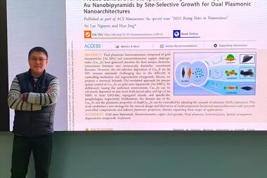 Hao Jing standing in front of a presentation of his research.