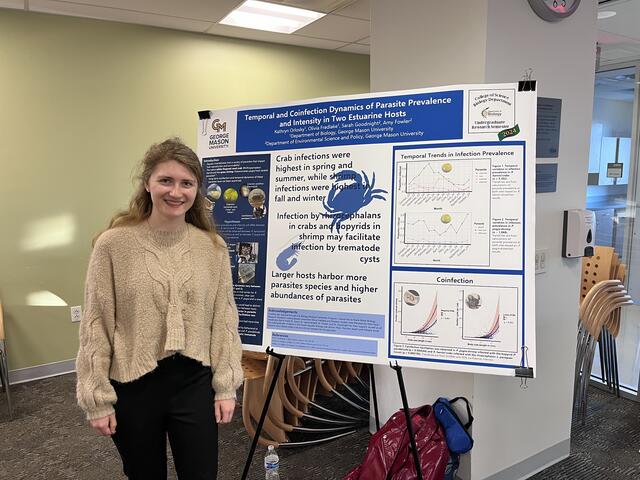 A student stands next to her research poster