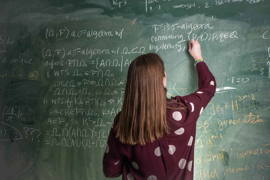 Student writing at a board